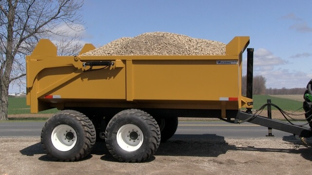A close-up image of the 12 ton off-road dumpster trailer full of mulch