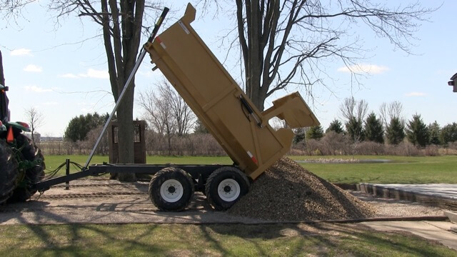 A close-up image of the 12 ton off-road dumper trailer dumping mulch