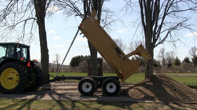 A close-up image of the 12 ton off-road dump trailer dumping mulch