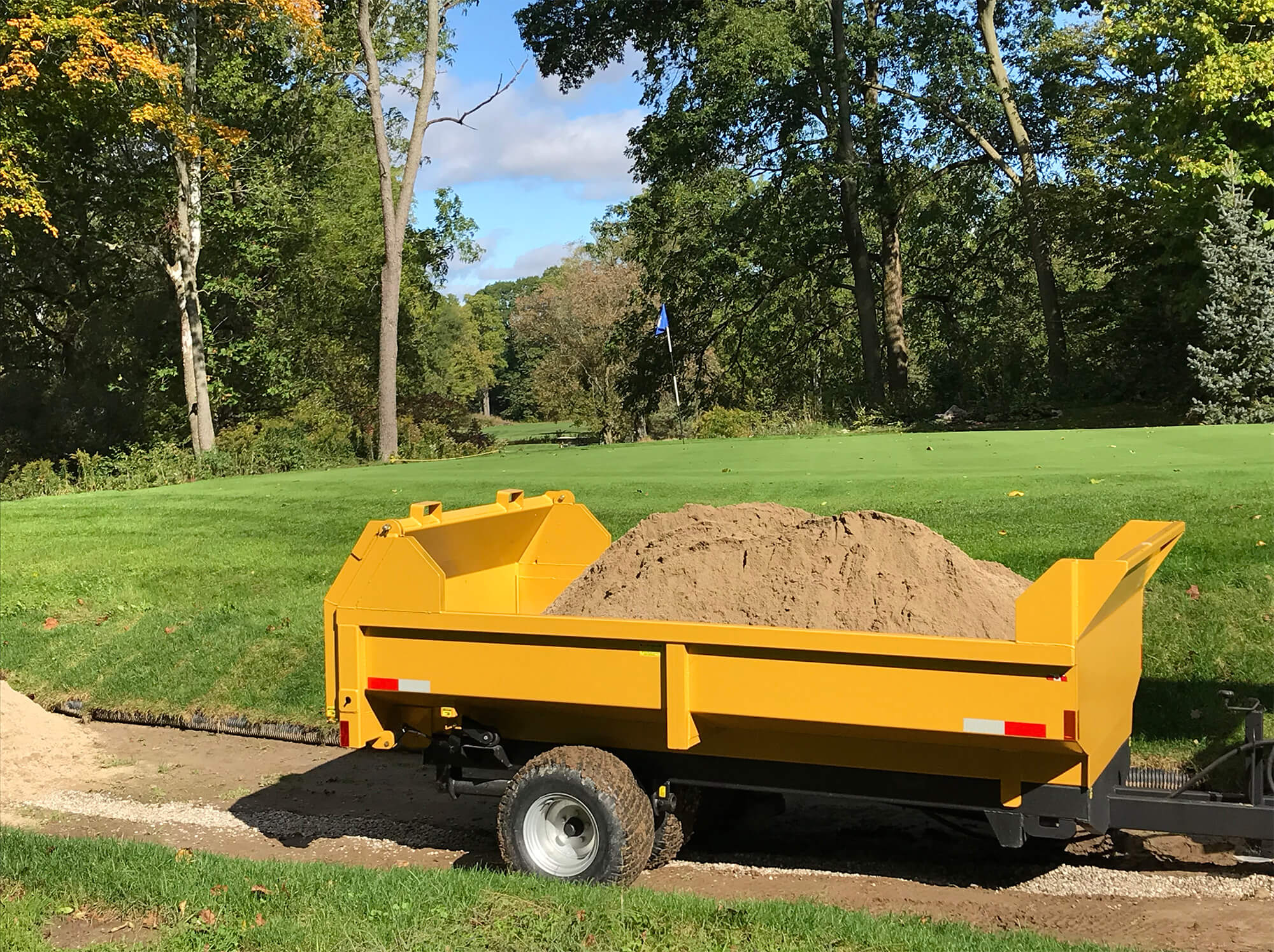 a side profile of the 5 ton turf dumpster trailer hauling dirt